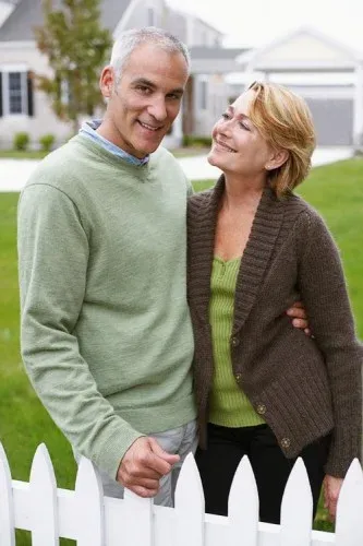 happy-couple-standing-by-white-fence-web