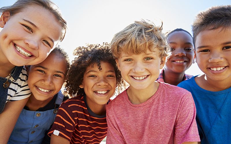 Close up of pre-teen friends in a park smiling to camera